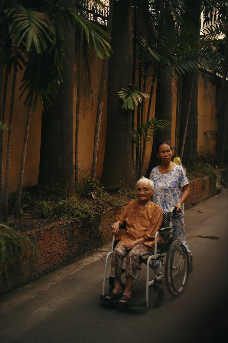 woman walking an elderly person on a wheelchair